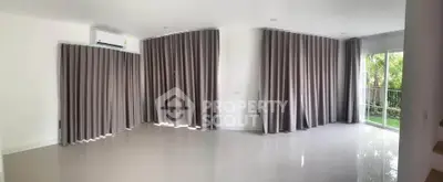 Spacious living room with large windows and elegant curtains, offering a bright and airy atmosphere.