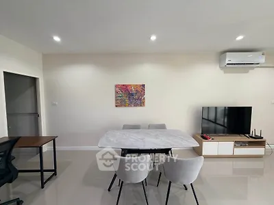 Modern living room with sleek furniture and wall art, featuring a TV and air conditioning.