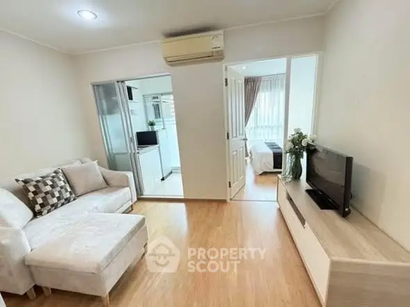 Cozy living room with modern decor and natural light, adjacent to a stylish bedroom.