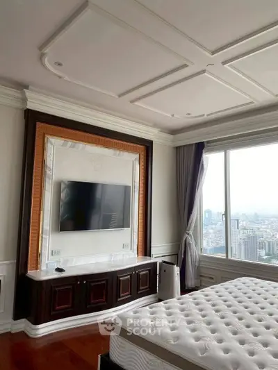 Luxurious bedroom with city view, featuring elegant ceiling design and wall-mounted TV.