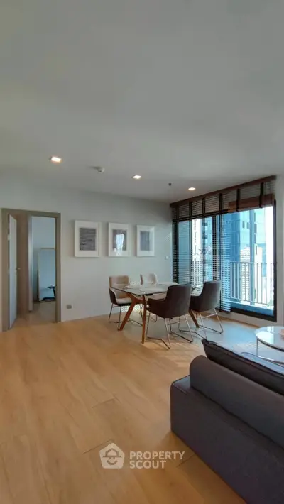 Modern living room with dining area and large windows in a high-rise apartment.