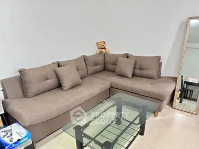 Cozy living room with plush sectional sofa and glass coffee table, perfect for relaxation and entertaining.