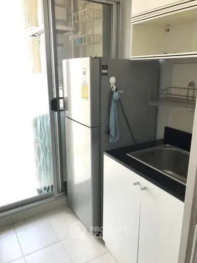 Compact kitchen with modern fridge and sink in bright apartment