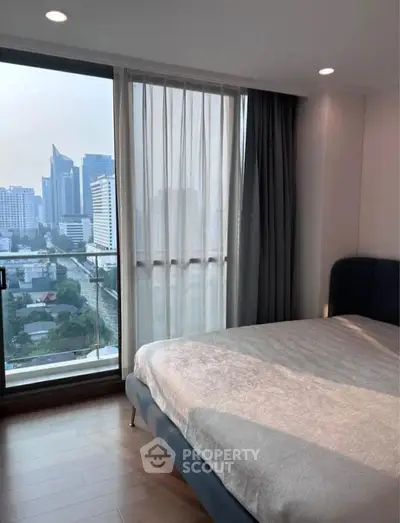 Modern bedroom with city view and large windows in high-rise apartment.