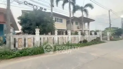 Charming two-story house with palm trees and a spacious front yard in a serene neighborhood.
