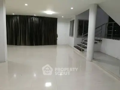 Spacious modern living room with sleek staircase and large windows.