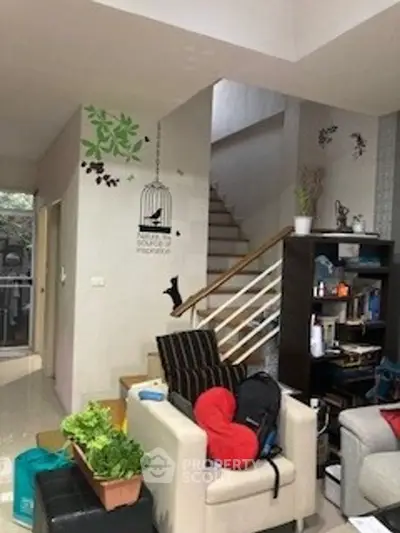Charming living room with modern decor and staircase, perfect for cozy family gatherings.