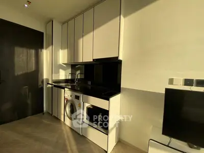 Modern kitchen with sleek cabinets, washing machine, and microwave in a compact layout.