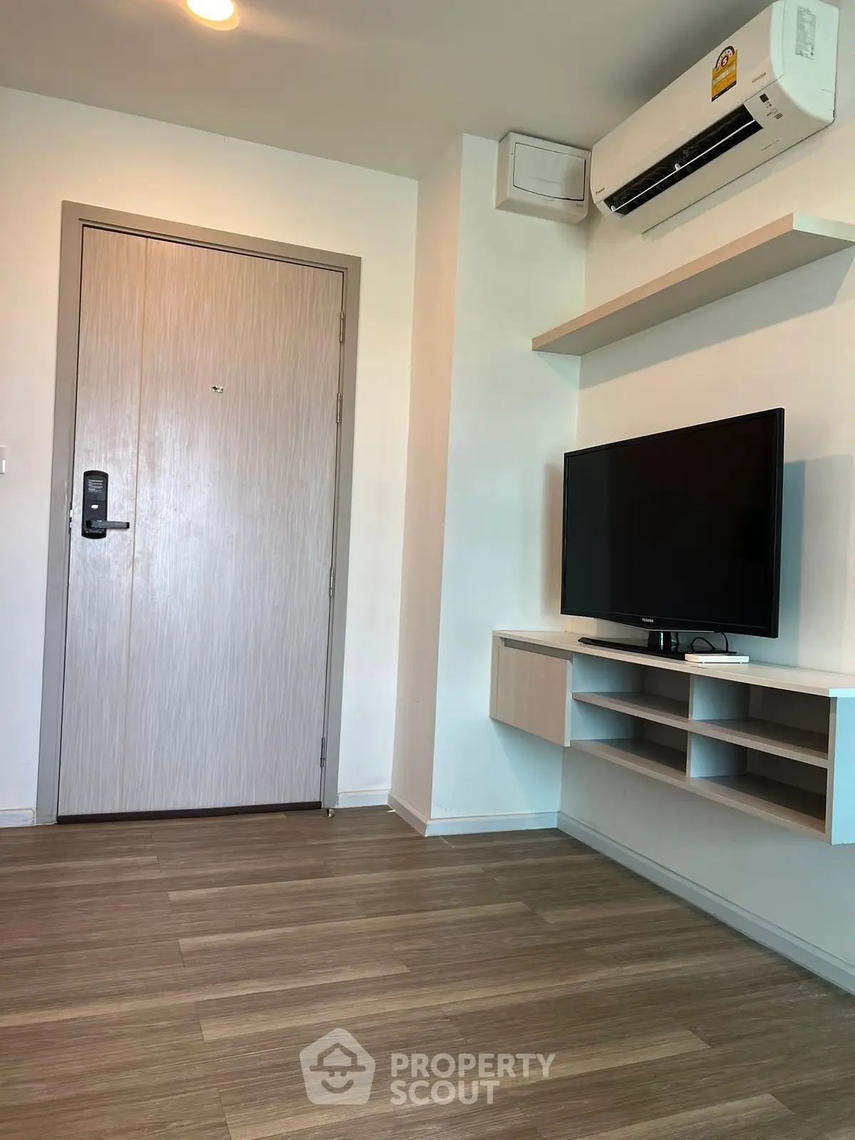 Modern living room with sleek TV setup and air conditioning unit.