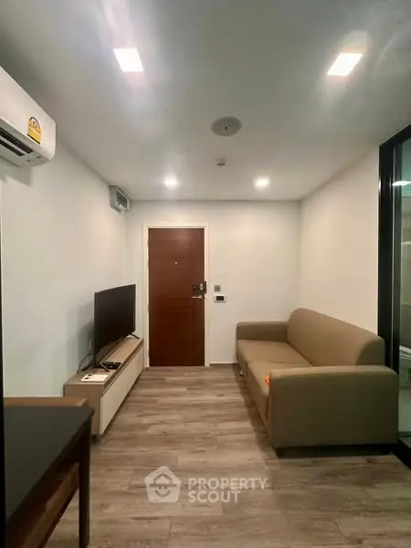Modern living room with sleek design, featuring a comfortable sofa and flat-screen TV.