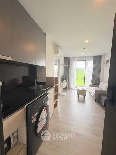 Modern apartment with open layout, featuring sleek kitchen and bright living area with balcony view.