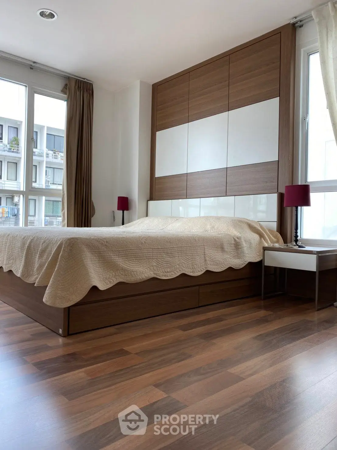 Modern bedroom with wooden flooring and large windows in a stylish apartment.