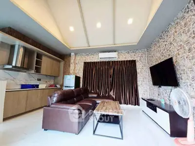 Modern living room with open kitchen, featuring leather sofa and wall-mounted TV.