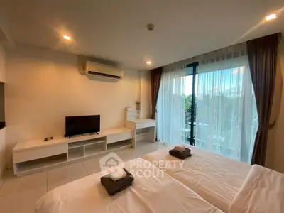 Spacious bedroom with twin beds, modern decor, and large window offering natural light and scenic views.
