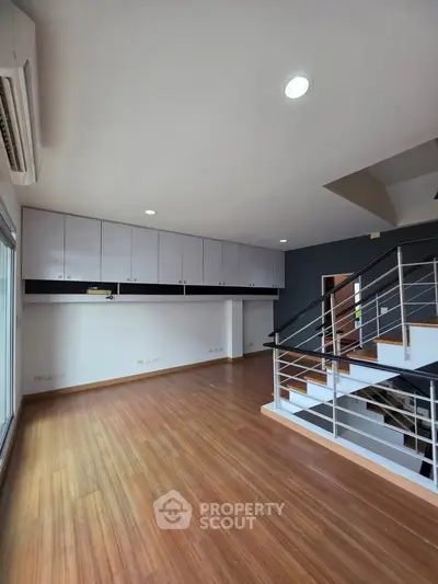 Spacious modern living room with wooden flooring and sleek staircase
