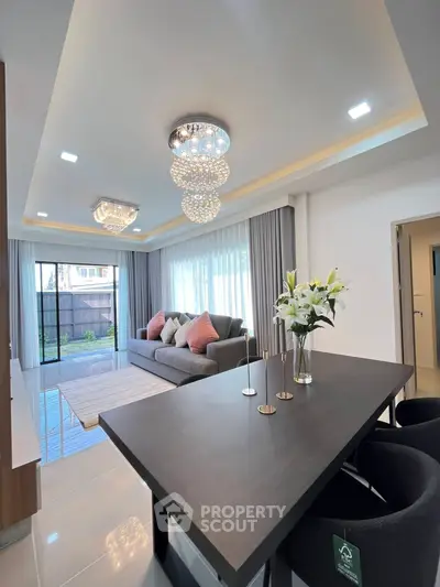 Luxurious living room with elegant chandeliers and modern decor, featuring a spacious layout and stylish furnishings.