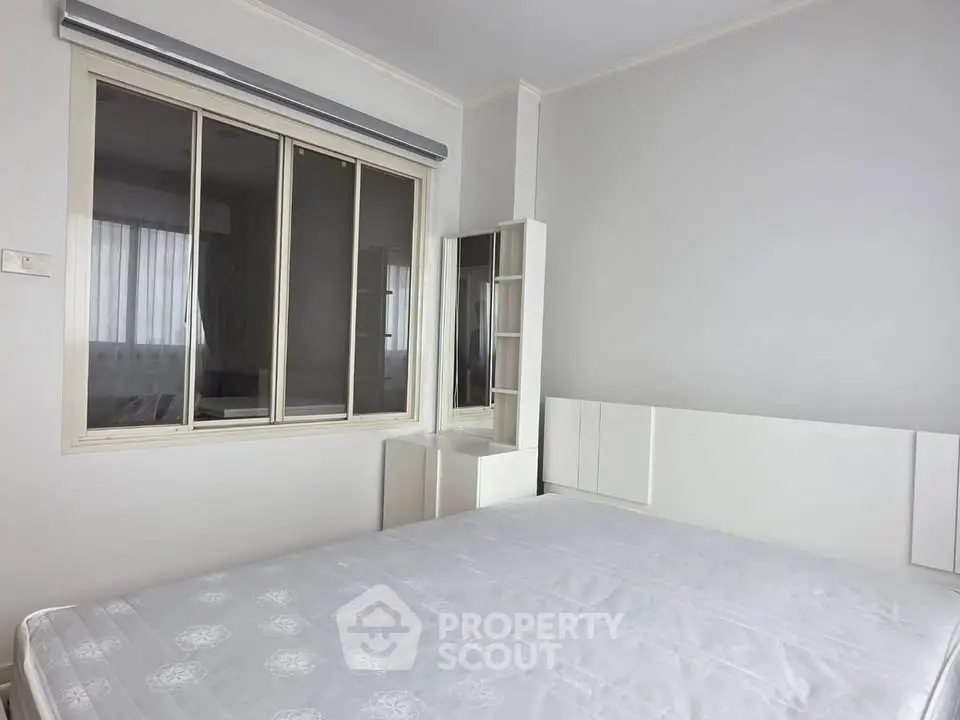 Spacious bedroom with large window and modern white furniture, perfect for a serene living experience.