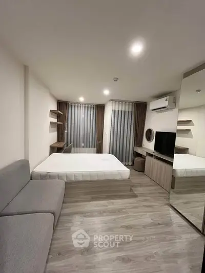 Modern bedroom with sleek design, featuring a cozy bed, stylish sofa, and large mirror.