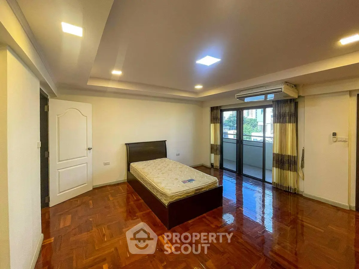 Spacious bedroom with balcony access and polished wooden floors
