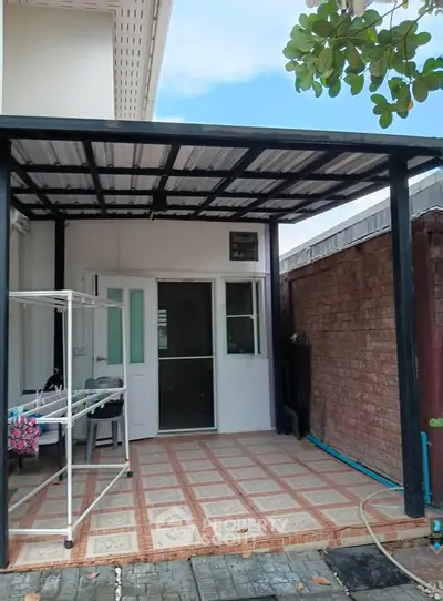 Charming outdoor patio with tiled flooring and covered roof, perfect for relaxation and laundry area.