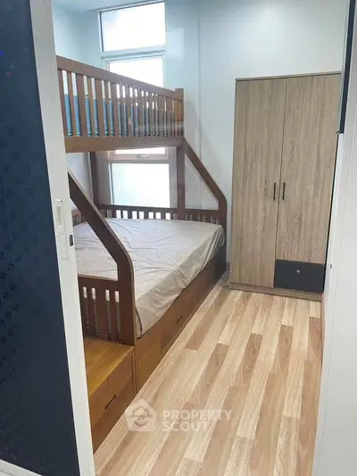 Cozy bedroom with wooden bunk bed and wardrobe, perfect for maximizing space in small apartments.