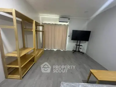 Spacious living room with modern TV setup and wooden shelving, perfect for cozy gatherings.