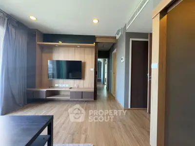 Spacious modern living room with wooden flooring and wall-mounted TV in a stylish apartment.