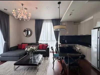 Elegant living room with modern kitchen, stylish chandelier, and cozy seating area.