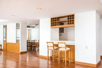 Spacious open-plan living area with elegant wooden flooring and built-in wine rack.