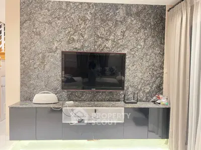 Modern living room with sleek TV setup and elegant stone accent wall