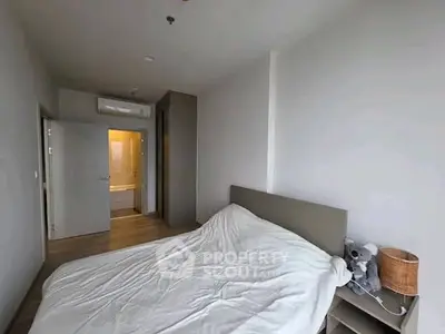 Cozy bedroom with minimalist decor and ensuite bathroom in modern apartment.