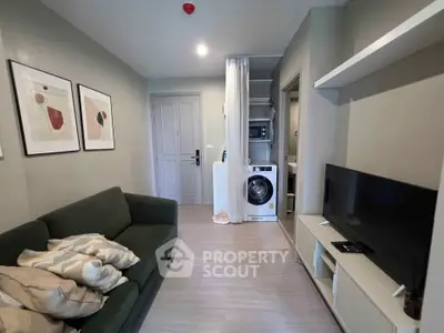 Modern living room with green sofa, wall art, and integrated laundry area in stylish apartment.