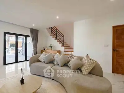 Modern living room with stylish curved sofa and staircase in elegant home