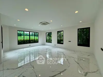 Spacious modern room with large windows and marble flooring, offering serene garden views.