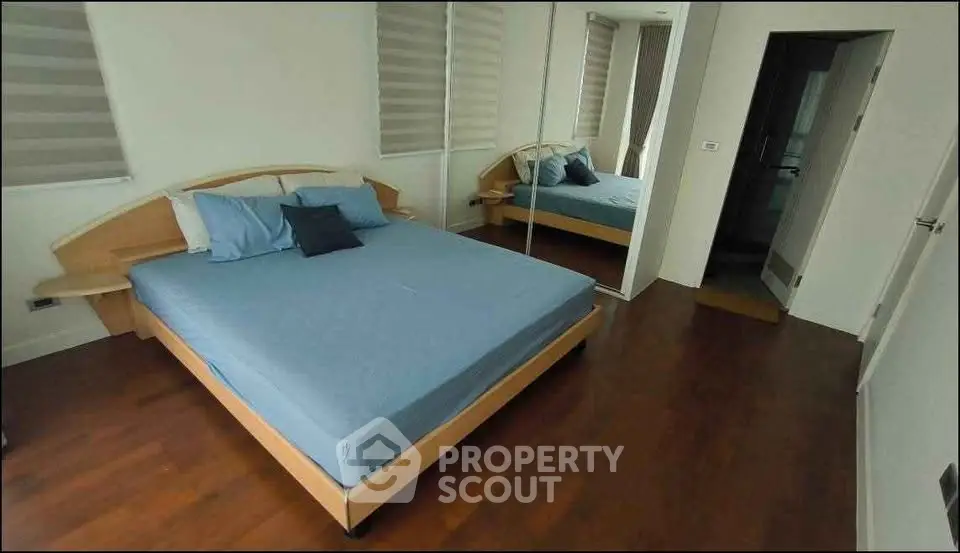 Spacious bedroom with wooden flooring and modern furnishings