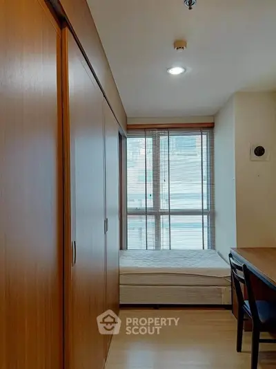 Cozy bedroom with wooden wardrobe and large window offering natural light