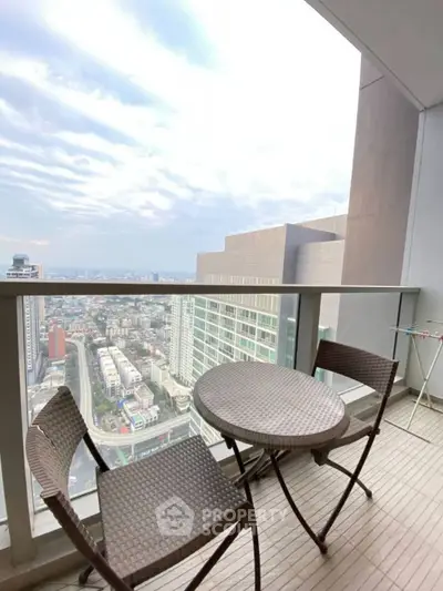 Stunning high-rise balcony with panoramic city views and cozy seating area.