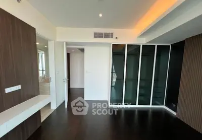 Spacious modern room with dark wood flooring and glass closet doors