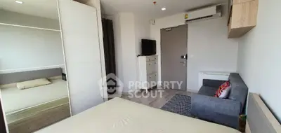 Modern bedroom with mirrored wardrobe and cozy seating area in stylish apartment