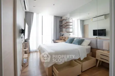 Modern bedroom with wooden flooring, mirrored wall, and ample natural light.