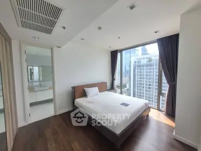 Modern bedroom with city view, featuring large windows and elegant wooden flooring.