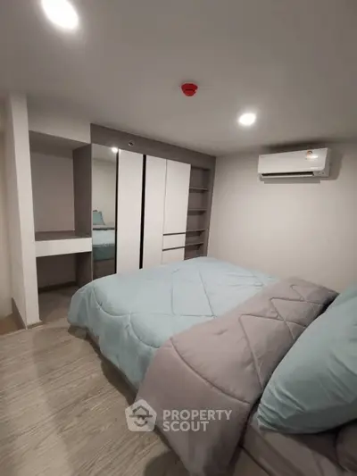 Modern bedroom with sleek design, featuring a cozy bed, built-in wardrobe, and air conditioning unit.