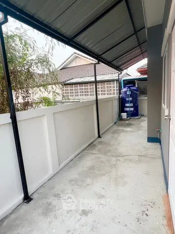 Covered outdoor area with concrete flooring and water tank, ideal for storage or utility use.