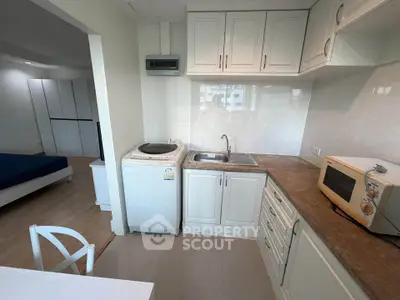 Charming compact kitchen with washing machine and microwave in modern apartment