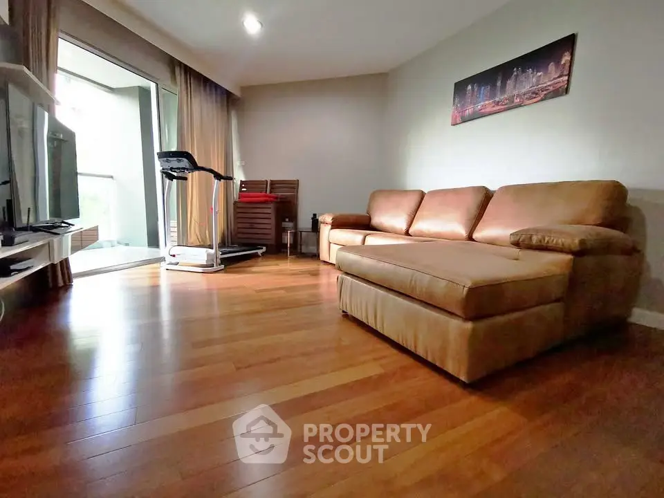 Spacious living room with hardwood floors and cozy leather sofa