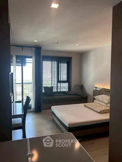 Modern bedroom with large window and cozy seating area, perfect for relaxation and comfort.