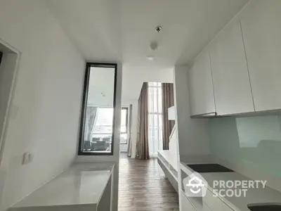 Modern kitchen with sleek white cabinets and open layout leading to a bright living area.