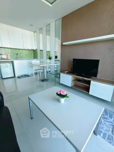 Modern open-layout living room with sleek kitchen, stylish decor, and natural light.