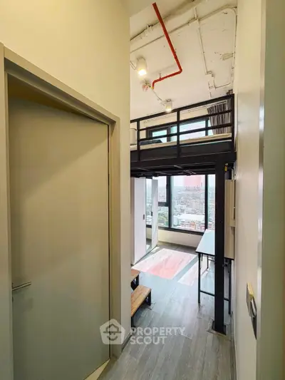 Modern loft apartment with high ceilings and large windows offering city views, featuring a mezzanine level.