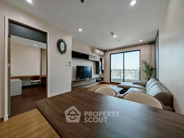 Spacious modern living room with large window and city view, featuring stylish furniture and open layout.